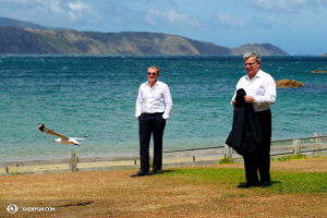 El director de orquesta Milen Nachev (der.), el violista Derek Hensler (izq.) y una gaviota de Nueva Zelanda disfrutan del viento que atraviesa la Bahía Fitzroy. (Foto del bailarín Ben Chen)